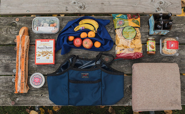 A possible grocery haul for a Monster Truck (a baguette, breakfast cereal, a bag of chips, some fruit, a 4 pack of beer, a pre-made sandwich and salad, yogurt and a jar of spread).